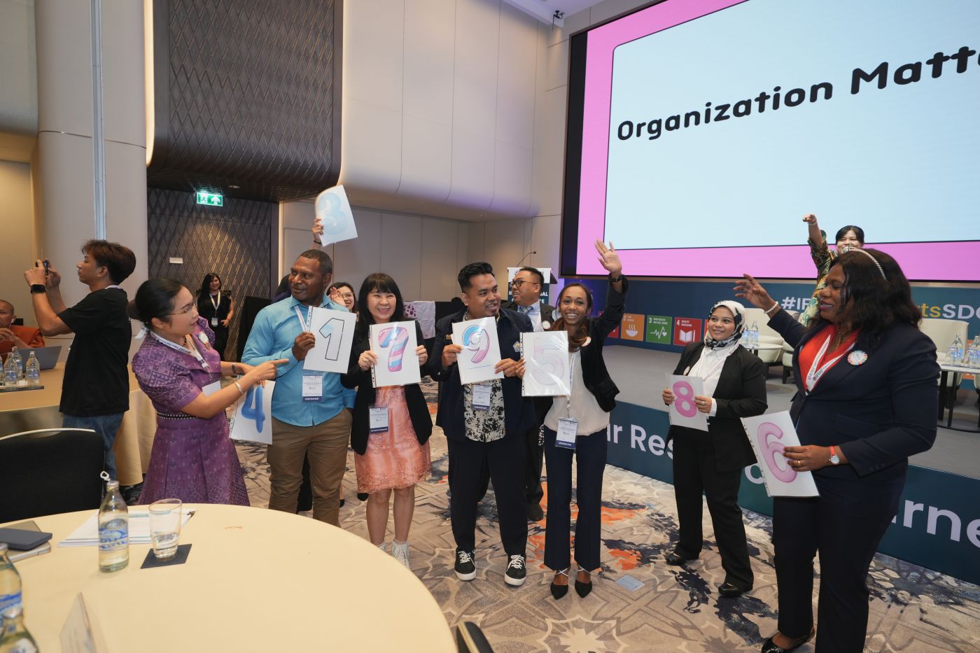 Delegates holding up numbered Sustainable Development Goal cards during a session